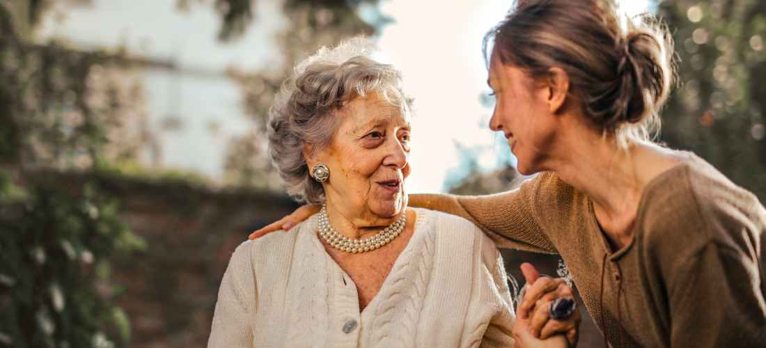 joyful adult daughter greeting happy surprised senior mother in garden