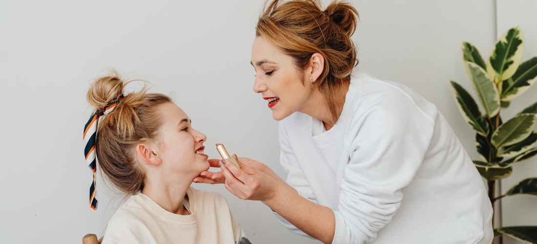 photograph of a mother applying lipstick on her daughter